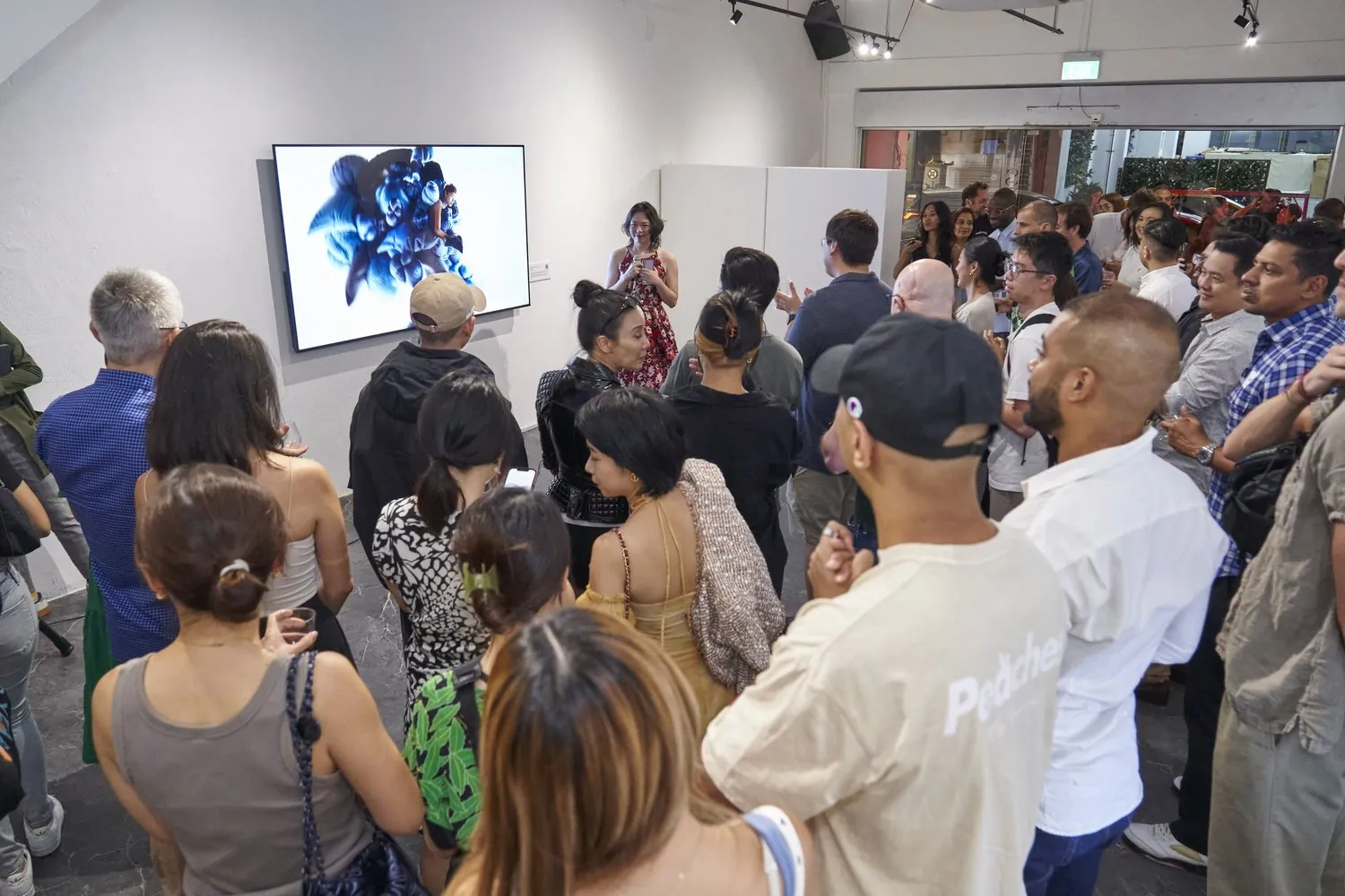 Opening night of The Ties That Bind, guests around the digital artwork The Weight of the World during an artist talk.