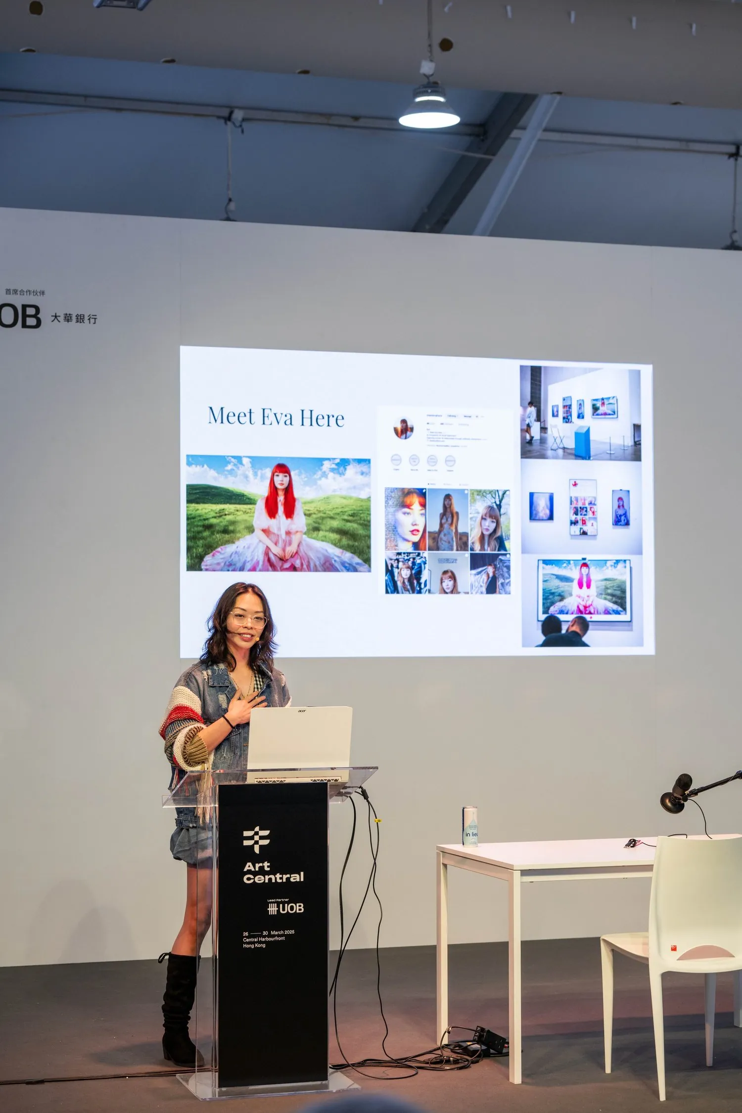 Shavonne Wong on stage at Art Central Hong Kong 2025, presenting Meet Eva Here with visual documentation projected behind her.