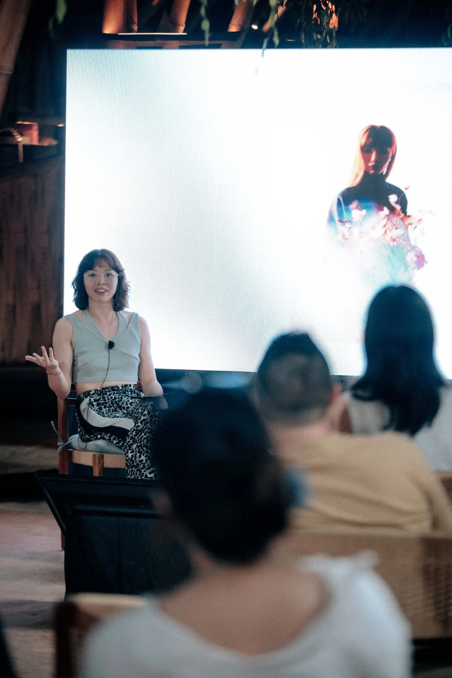 Shavonne Wong speaking during a panel at Silk Art House: Chapter 2 in Bali, Eva's digital portrait projected behind her.